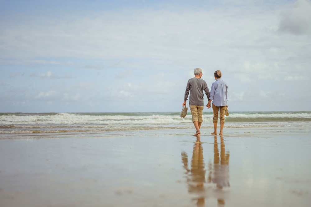 Couple marchant sur la plage au lever du soleil